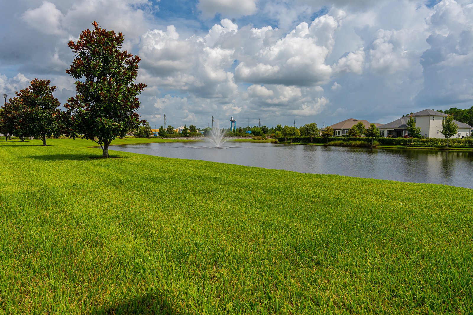 Retention pond with an aerating fountain and a manicured grass bank in an HOA community